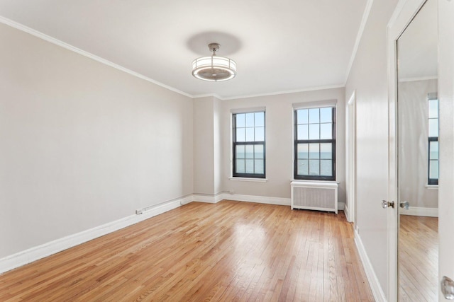 spare room featuring ornamental molding, radiator heating unit, and light hardwood / wood-style flooring