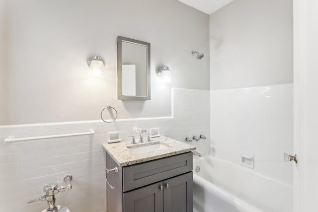 bathroom with vanity, tile walls, and a tub