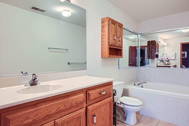 bathroom featuring toilet, vanity, tiled bath, and tile patterned flooring