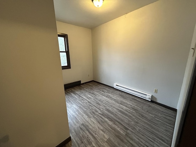 empty room with dark wood-type flooring and baseboard heating