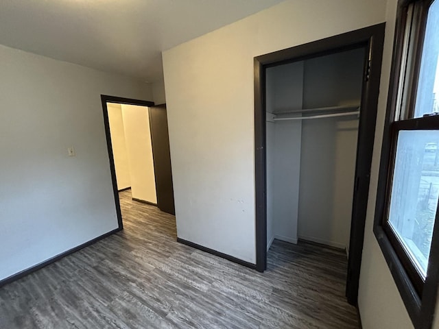 unfurnished bedroom with dark wood-type flooring and a closet