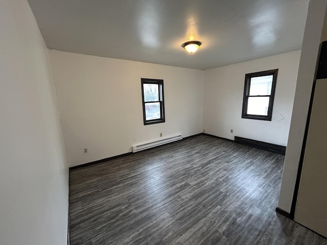 spare room with a baseboard heating unit and dark hardwood / wood-style floors