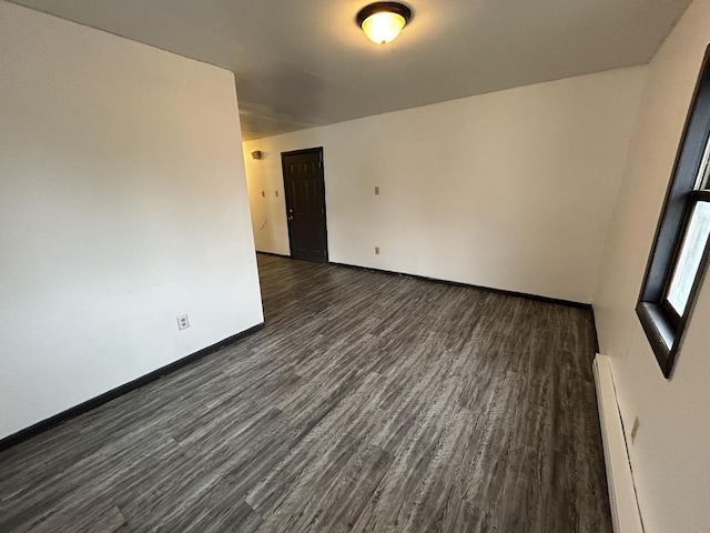 spare room with dark hardwood / wood-style flooring and baseboard heating