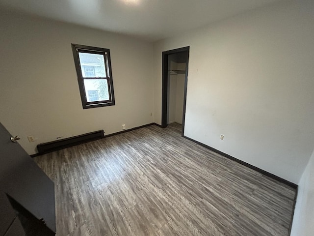 unfurnished room with hardwood / wood-style floors and a baseboard heating unit