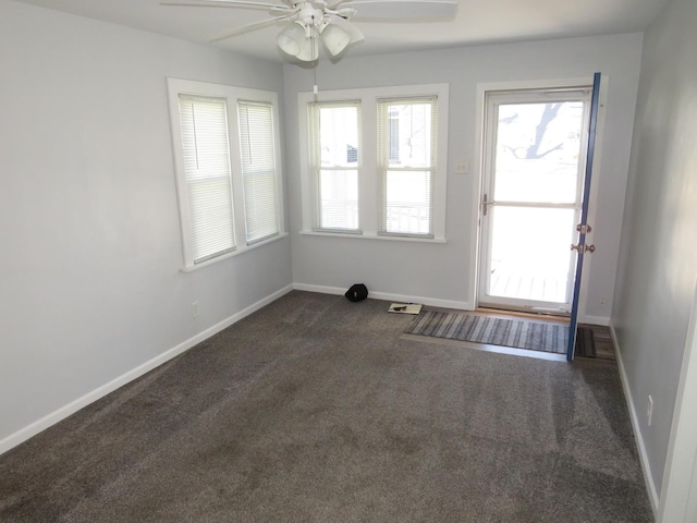 empty room with ceiling fan and dark colored carpet