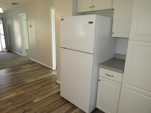 kitchen with white refrigerator, dark wood-type flooring, and white cabinets