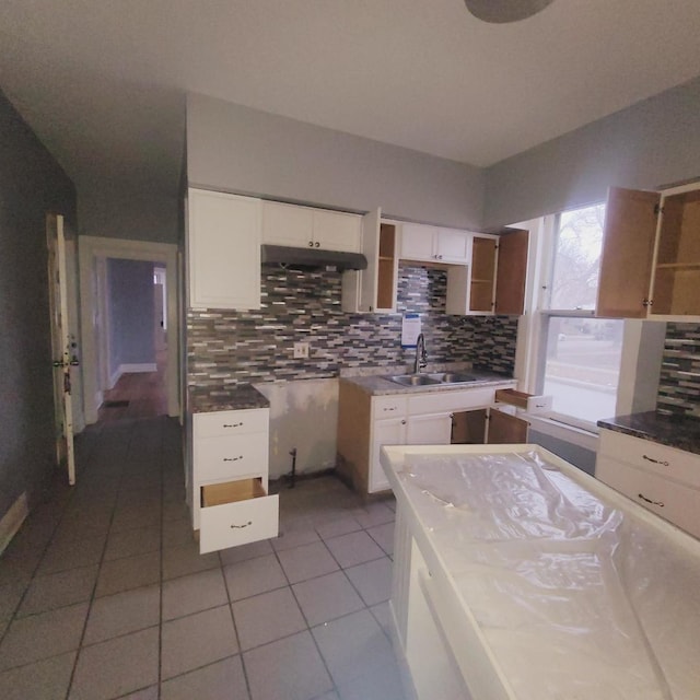 kitchen featuring sink, light tile patterned floors, white cabinets, and backsplash