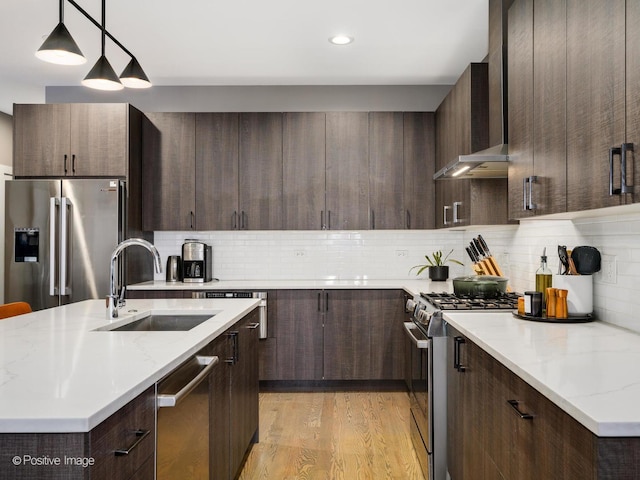 kitchen featuring pendant lighting, sink, appliances with stainless steel finishes, dark brown cabinetry, and light wood-type flooring