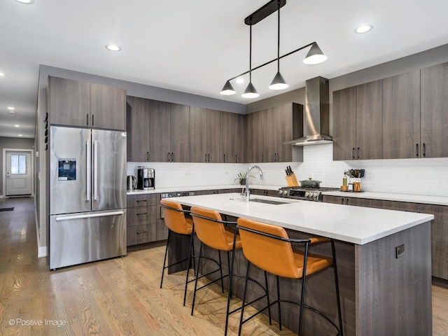 kitchen featuring appliances with stainless steel finishes, sink, dark brown cabinets, and wall chimney exhaust hood