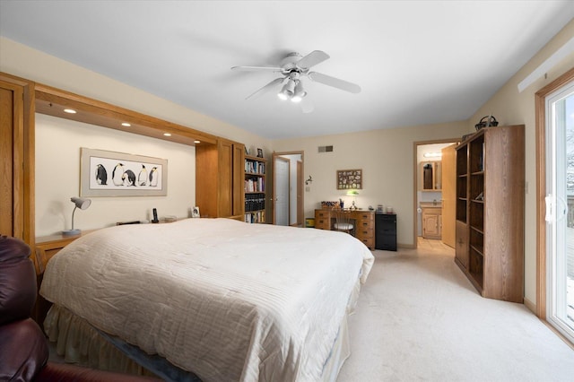 bedroom with ensuite bathroom, light carpet, and ceiling fan