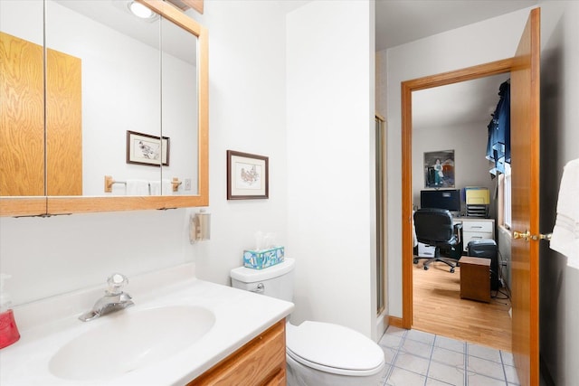 bathroom with vanity, a shower with shower door, tile patterned floors, and toilet