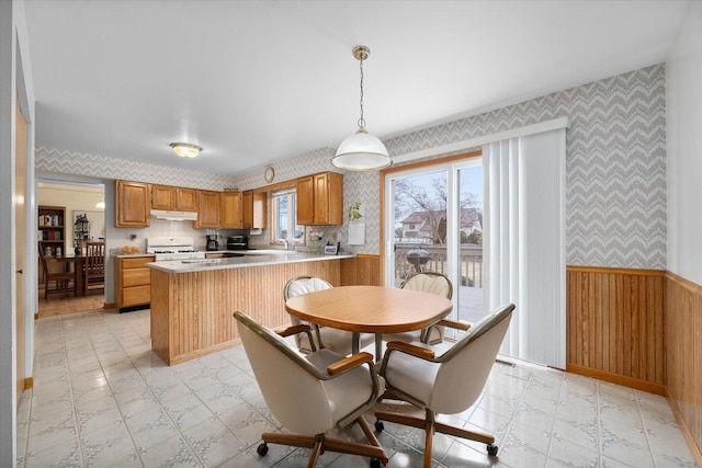 kitchen with hanging light fixtures, sink, white gas stove, and kitchen peninsula