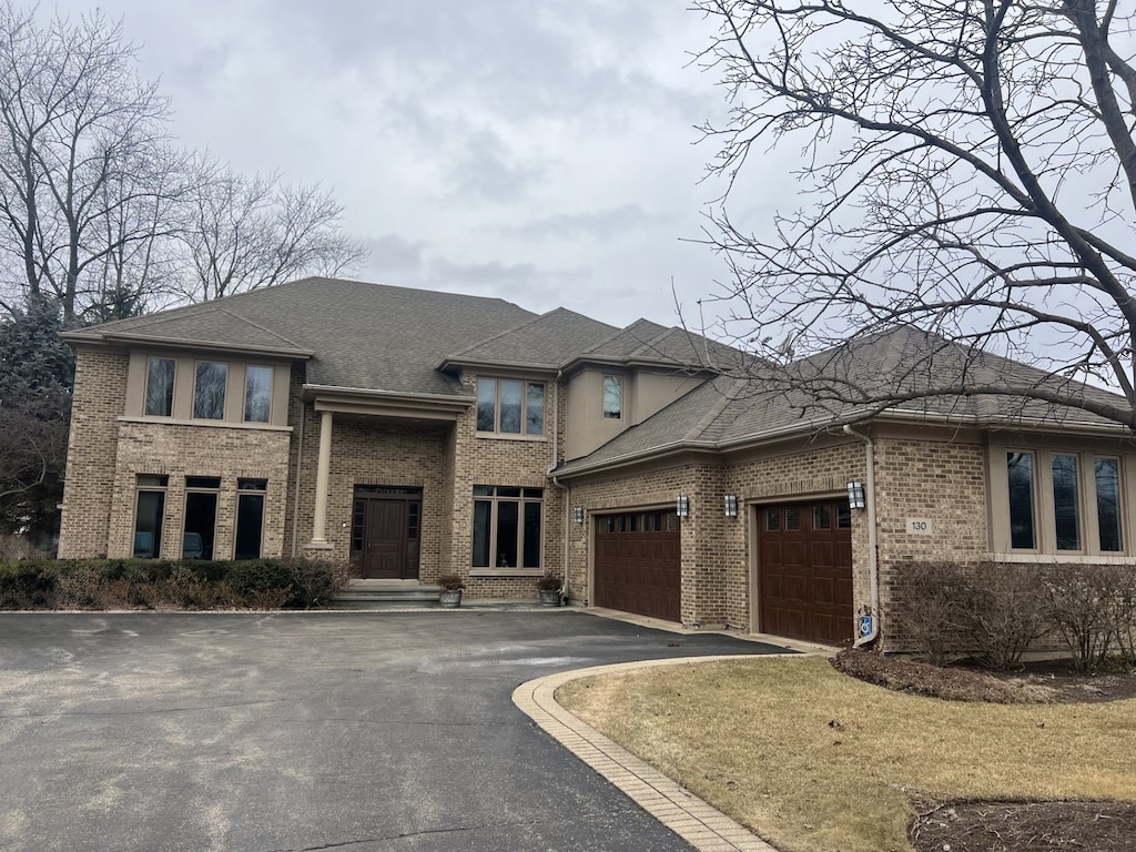 prairie-style house featuring aphalt driveway, brick siding, an attached garage, and a shingled roof