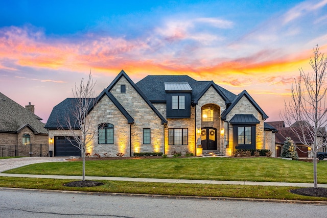 french country home featuring a garage and a lawn