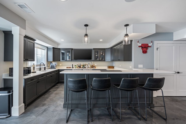 kitchen featuring hanging light fixtures, a breakfast bar, sink, and kitchen peninsula