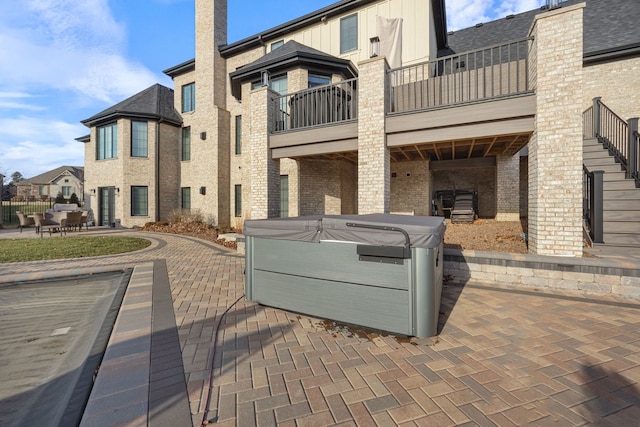 view of patio / terrace featuring a hot tub and a balcony