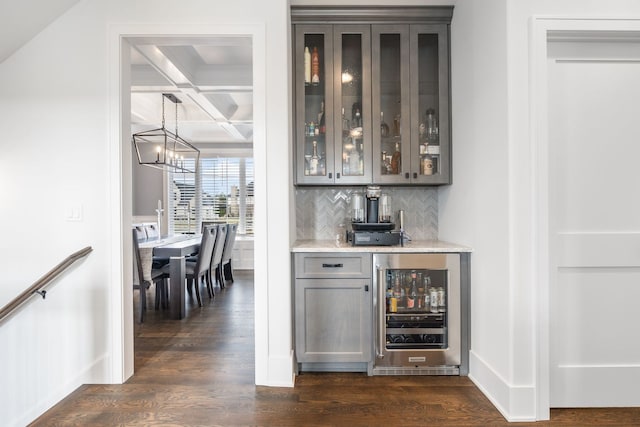 bar featuring dark wood-type flooring, coffered ceiling, beverage cooler, and pendant lighting