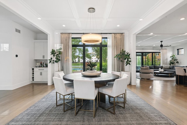 dining space with baseboards, visible vents, coffered ceiling, and wood finished floors