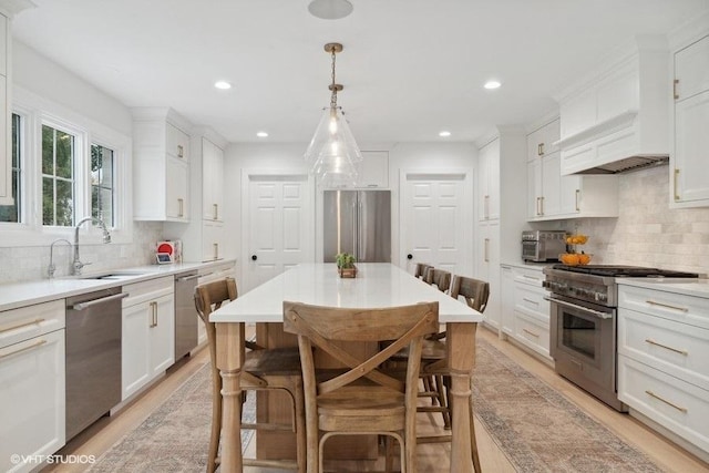 kitchen featuring light wood finished floors, high quality appliances, white cabinetry, and a sink