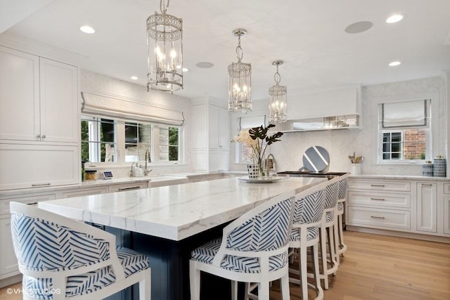 kitchen with a kitchen bar, a sink, white cabinets, and a center island