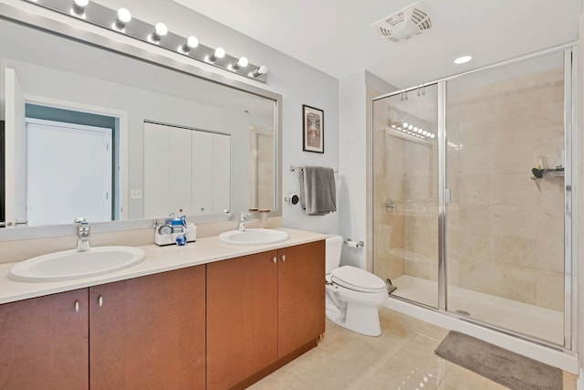 bathroom with vanity, toilet, a shower with shower door, and tile patterned flooring