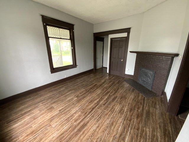 unfurnished living room featuring a brick fireplace and dark hardwood / wood-style floors