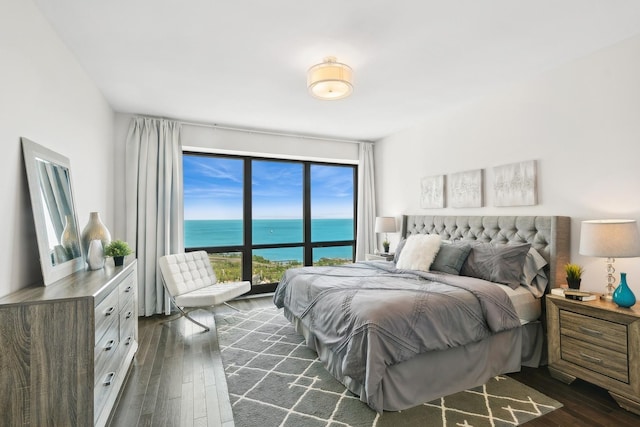 bedroom with a water view and dark hardwood / wood-style floors