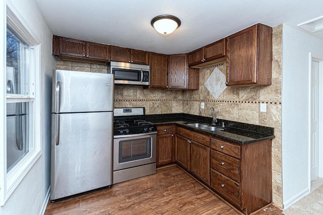 kitchen with sink, dark stone countertops, stainless steel appliances, dark hardwood / wood-style floors, and decorative backsplash