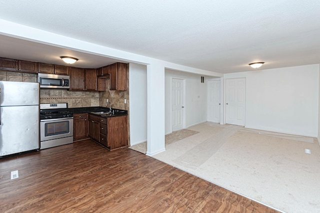 kitchen featuring tasteful backsplash, sink, dark hardwood / wood-style flooring, stainless steel appliances, and a textured ceiling