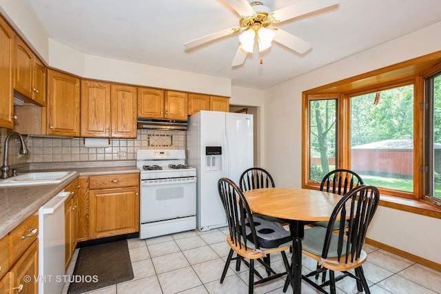 kitchen featuring tasteful backsplash, white appliances, light tile patterned flooring, and sink