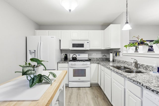 kitchen with sink, light wood-type flooring, white cabinets, hanging light fixtures, and white appliances