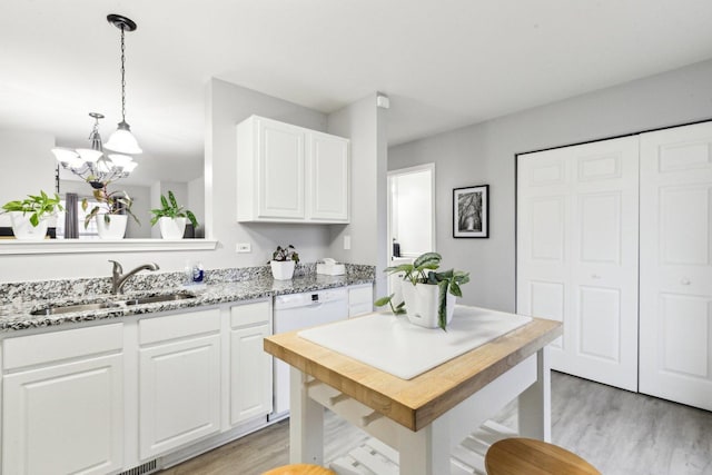 kitchen with sink, white cabinetry, decorative light fixtures, light wood-type flooring, and a kitchen island