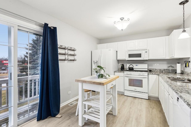 kitchen featuring white cabinetry, hanging light fixtures, light hardwood / wood-style floors, light stone countertops, and white appliances