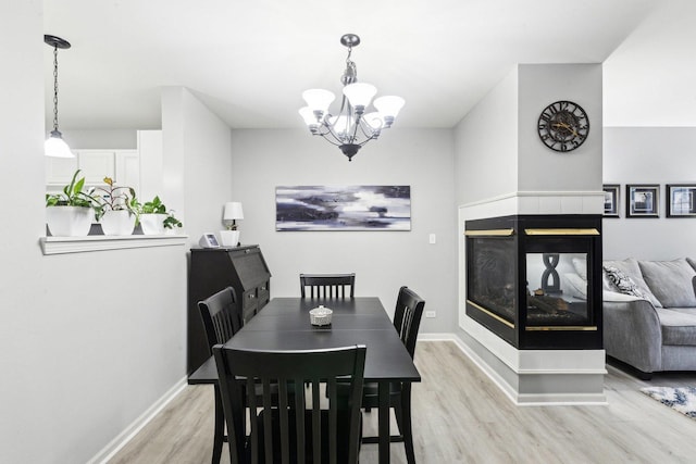 dining space featuring an inviting chandelier, light wood-type flooring, and a multi sided fireplace