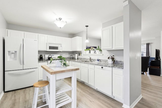 kitchen with decorative light fixtures, sink, white cabinets, light stone counters, and white appliances