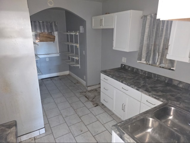 kitchen with white cabinetry, sink, and dark stone countertops