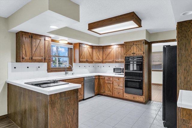 kitchen with kitchen peninsula, sink, decorative backsplash, and black appliances