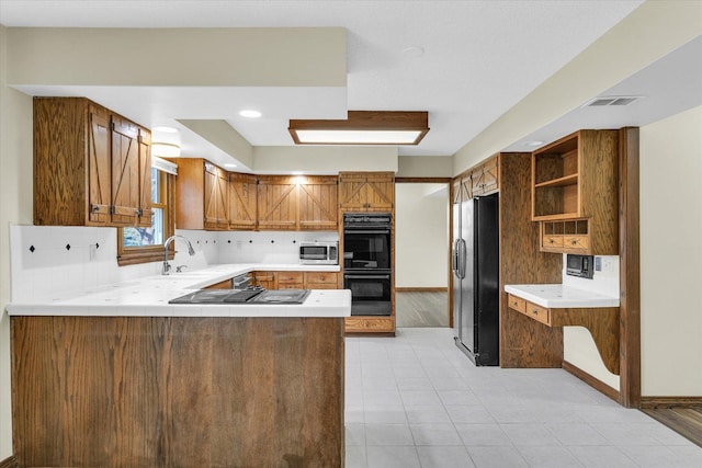 kitchen featuring tasteful backsplash, sink, kitchen peninsula, and black appliances