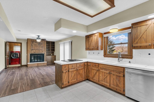 kitchen featuring sink, black cooktop, dishwasher, ceiling fan, and a fireplace