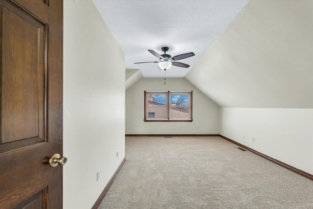 bonus room with ceiling fan, vaulted ceiling, light carpet, and a textured ceiling