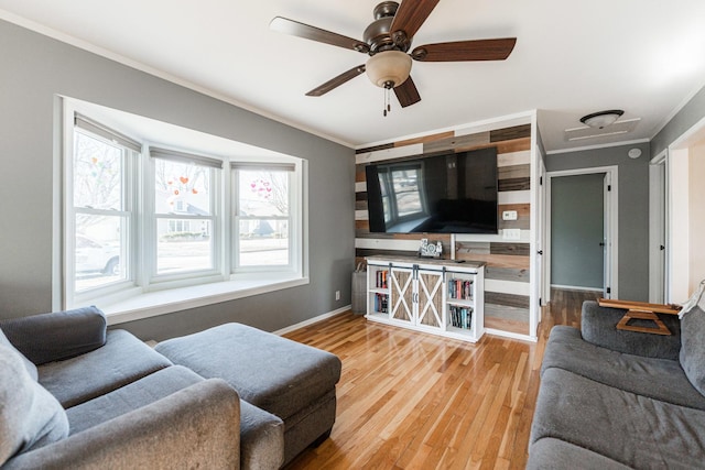 living room with hardwood / wood-style flooring, ornamental molding, and ceiling fan