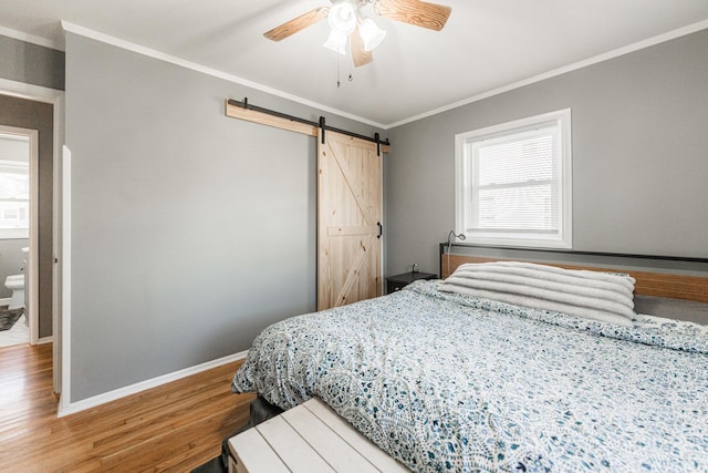 bedroom featuring crown molding, ceiling fan, wood-type flooring, and a barn door