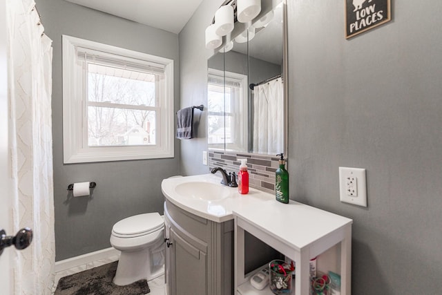 bathroom featuring vanity, backsplash, and toilet