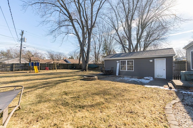 view of yard featuring a playground, an outbuilding, and a fire pit