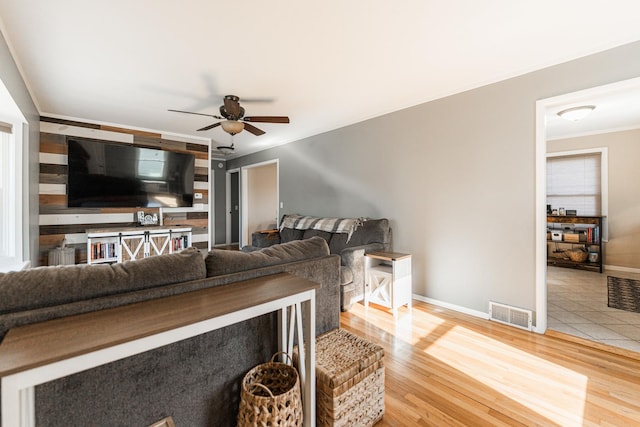 living room with ornamental molding, wood-type flooring, and ceiling fan