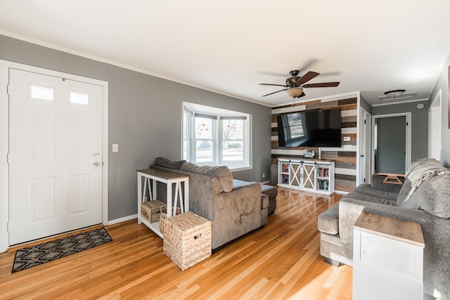 living room with crown molding, wood-type flooring, and ceiling fan