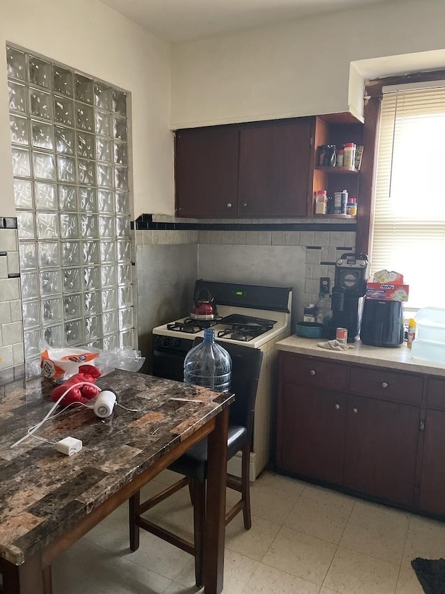 kitchen featuring gas stove, dark brown cabinets, and decorative backsplash