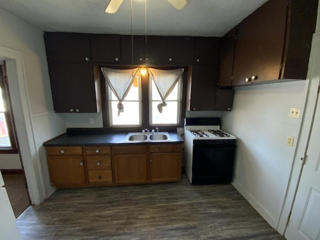 kitchen featuring ceiling fan, sink, white range with gas stovetop, and dark wood-type flooring