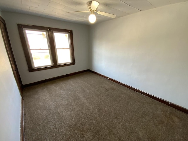 spare room featuring ceiling fan and dark carpet