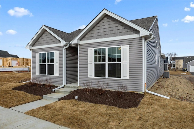 view of front of house with cooling unit and a front lawn